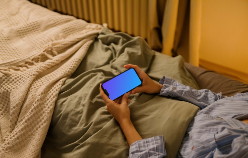 Mulher na cama segurando um iPhone mockup