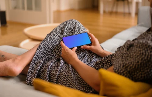 Woman laying on sofa holding a Google Pixel mockup