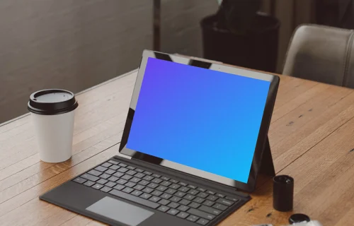 Black Microsoft Surface laptop mockup on a table beside a cup of coffee 
