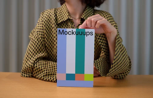 C-format book mockup held by person on wooden table