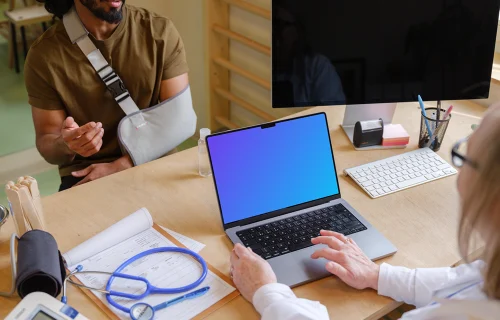 Doctor typing on laptop while talking with the patient