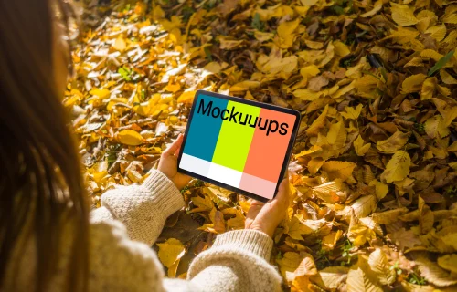 Female hands holding an iPad Air in the leaves mockup