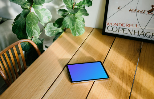 iPad Air mockup on a dining table in front of a framed photo 