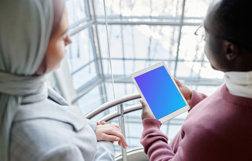 iPad Mini mockup held by a user in with a lady beside him