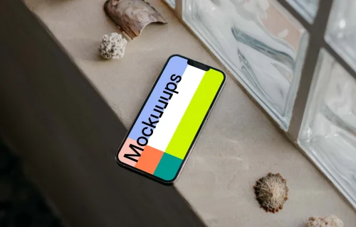 iPhone 13 Pro mockup by a window beside some seashells