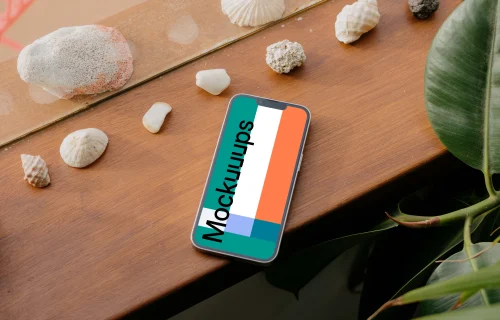 iPhone 13 Pro mockup on a wooden table next to seashells