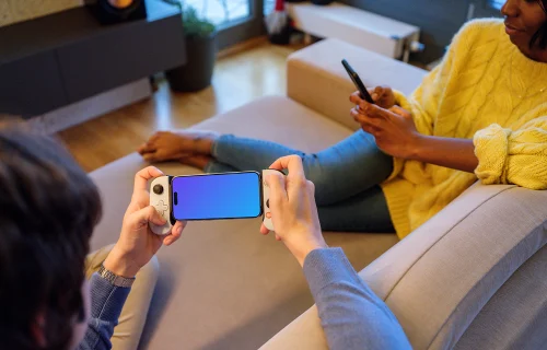 iPhone 15 Pro mockup in a gamer's hand on a couch
