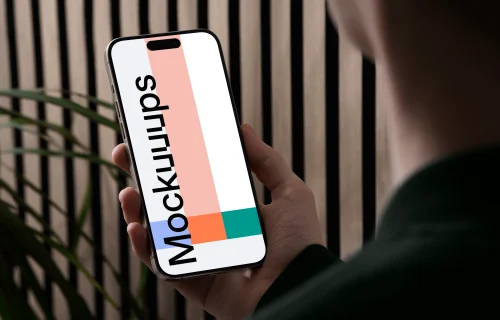 iPhone 15 Pro mockup in a male hand against a modern backdrop