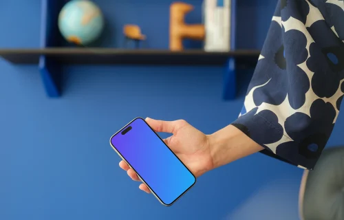 iPhone 15 Pro mockup in a woman's hand against a modern blue wall