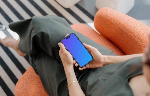 iPhone 15 Pro mockup in a woman's hand on a cozy couch