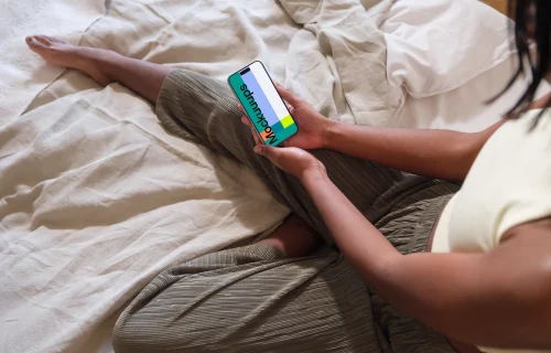 iPhone 15 Pro mockup in female hands on a cozy bed