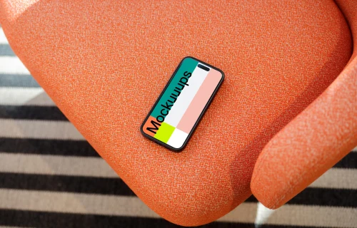 iPhone 15 Pro mockup on a vibrant orange armchair