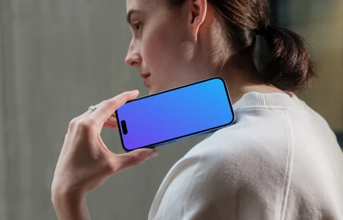 iPhone 16 mockup held by woman near concrete wall