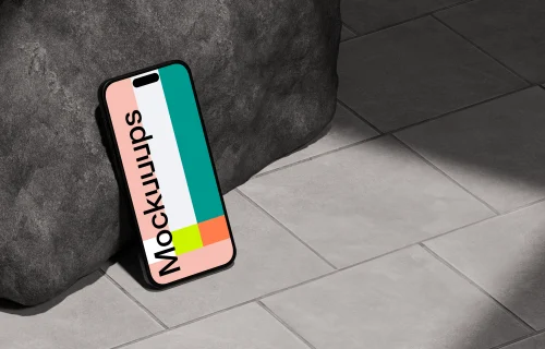 iPhone 16 mockup leaning against a rock on tiled floor