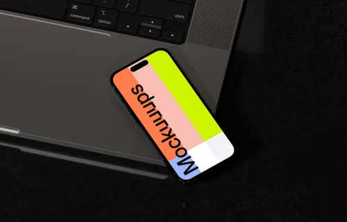 iPhone 16 mockup with laptop on black surface