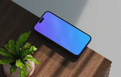 iPhone 17 mockup on a wooden desk with a plant