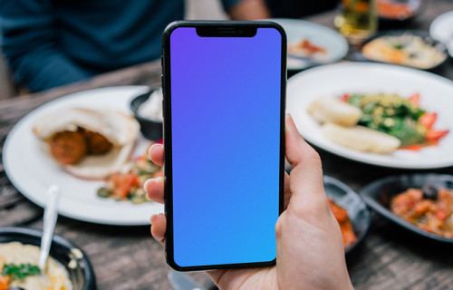 iPhone mockup held at lunch table
