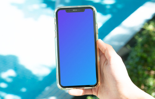 iPhone mockup held by user beside a swimming pool