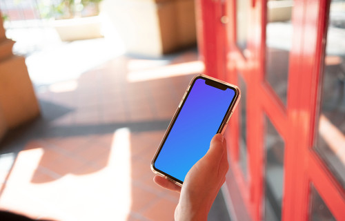 iPhone mockup held near red door.