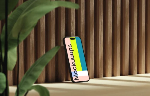 iPhone mockup on a wooden surface with a plant