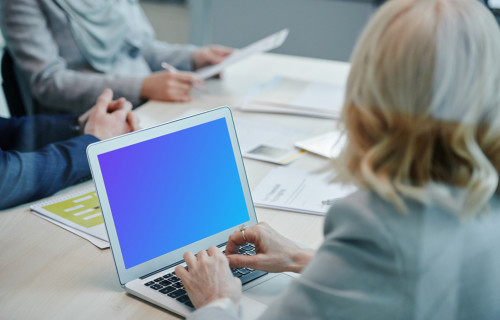 Lady at a conference table using a MacBook Air mockup