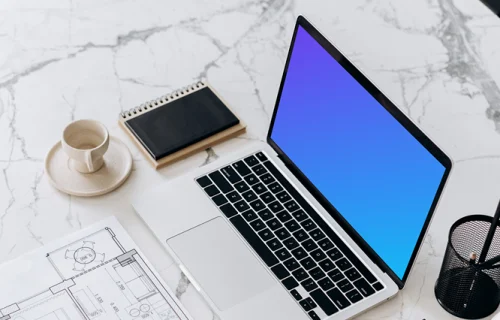 Laptop mockup on a table beside a house plan
