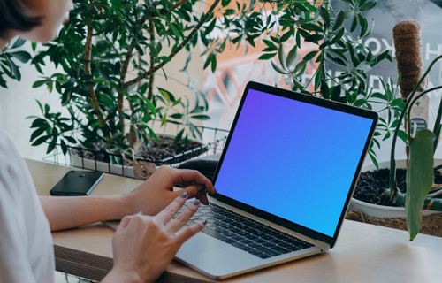 MacBook Air mockup in use by a lady with a lot of plants in the background