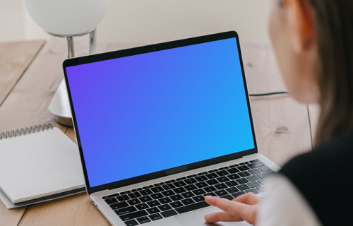 MacBook Air mockup in use by a lady with a notepad at the side