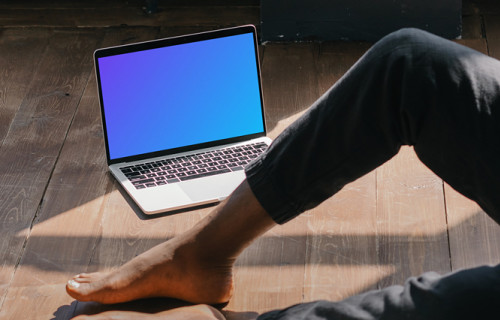 MacBook Air mockup placed on a wooden floor next to a user