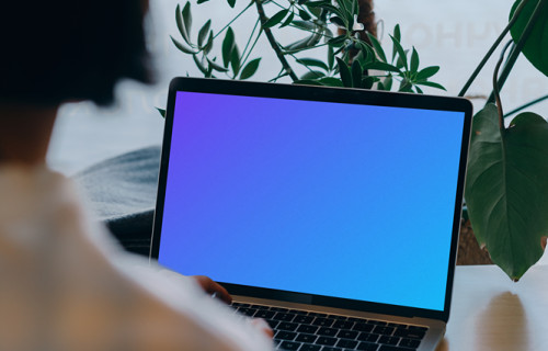 MacBook mockup in front of a user with plants in the background