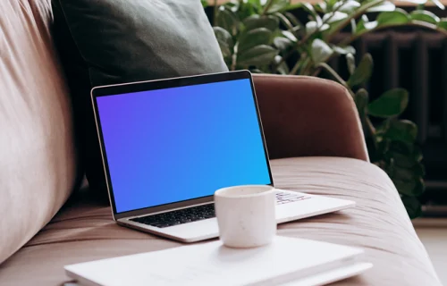 MacBook Pro mockup on a sofa with coffee and documents
