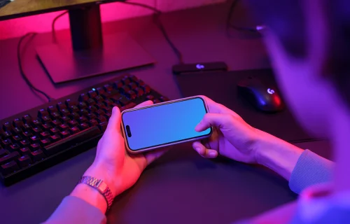 Male hands holding an iPhone mockup in gaming room