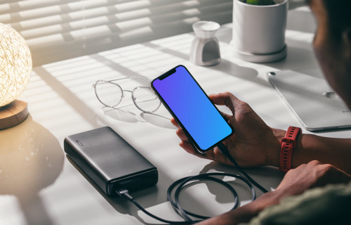 Man holding an iPhone 12 mockup plugged into a power bank