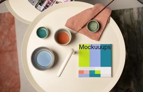 Mockup of a square poster with art supplies on a round table