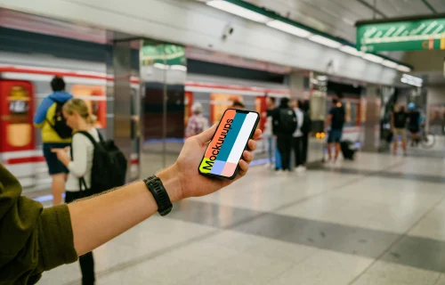 Person's hand holding an iPhone 13 mockup