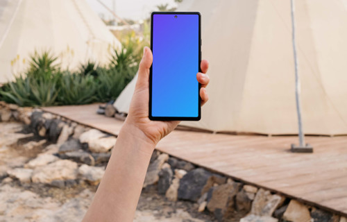 Pixel 6 mockup held by a user at an outdoor campsite