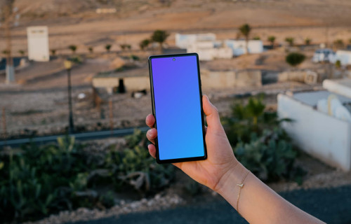 Smartphone mockup held by user over an open field