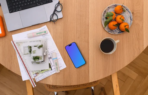 Smartphone mockup with architectural plans on a wooden table