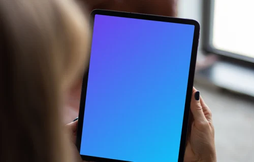 Tablet mockup held by user beside a window