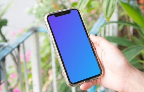 User holding up iPhone in a garden mockup