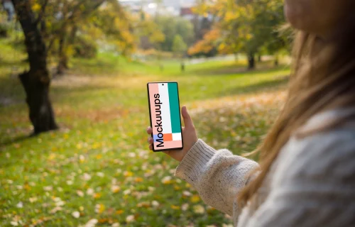 Woman hand holding a phone mockup in the autumn season