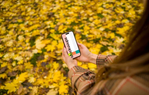 Woman hands holding an iPhone 14 Pro in autumn theme mockup