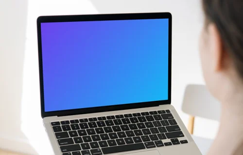 Woman holding a MacBook Pro mockup in a bright room