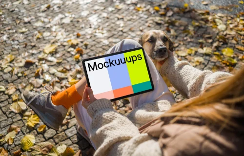 Woman holding a tablet in the park scratching dog mockup