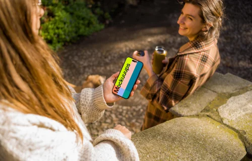 Woman holding an iPhone 14 Pro next to the friend mockup