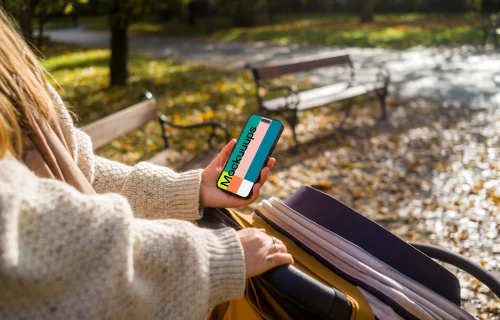 Woman holding an iPhone while walking in a park mockup