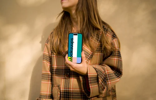 Woman in coat holding an iPhone 14 Pro mockup