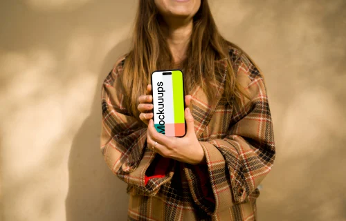 Woman in coat holding an iPhone mockup