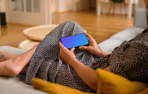 Woman laying on sofa holding a Google Pixel mockup