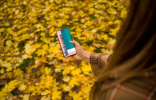 Woman scrolling on an iPhone 14 Pro in autumn season mockup